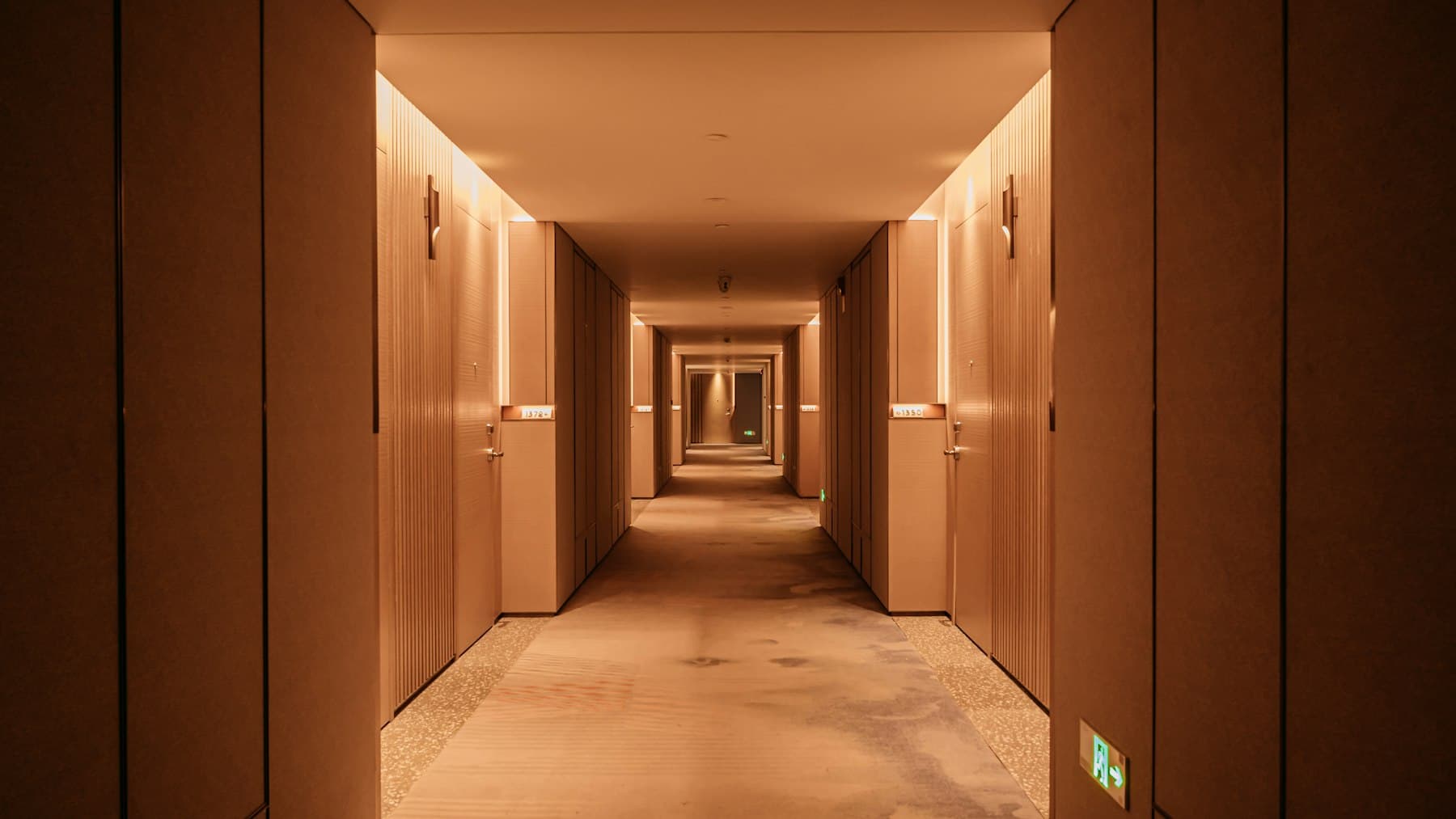 A warmly lit hotel corridor with timber-panelled walls.